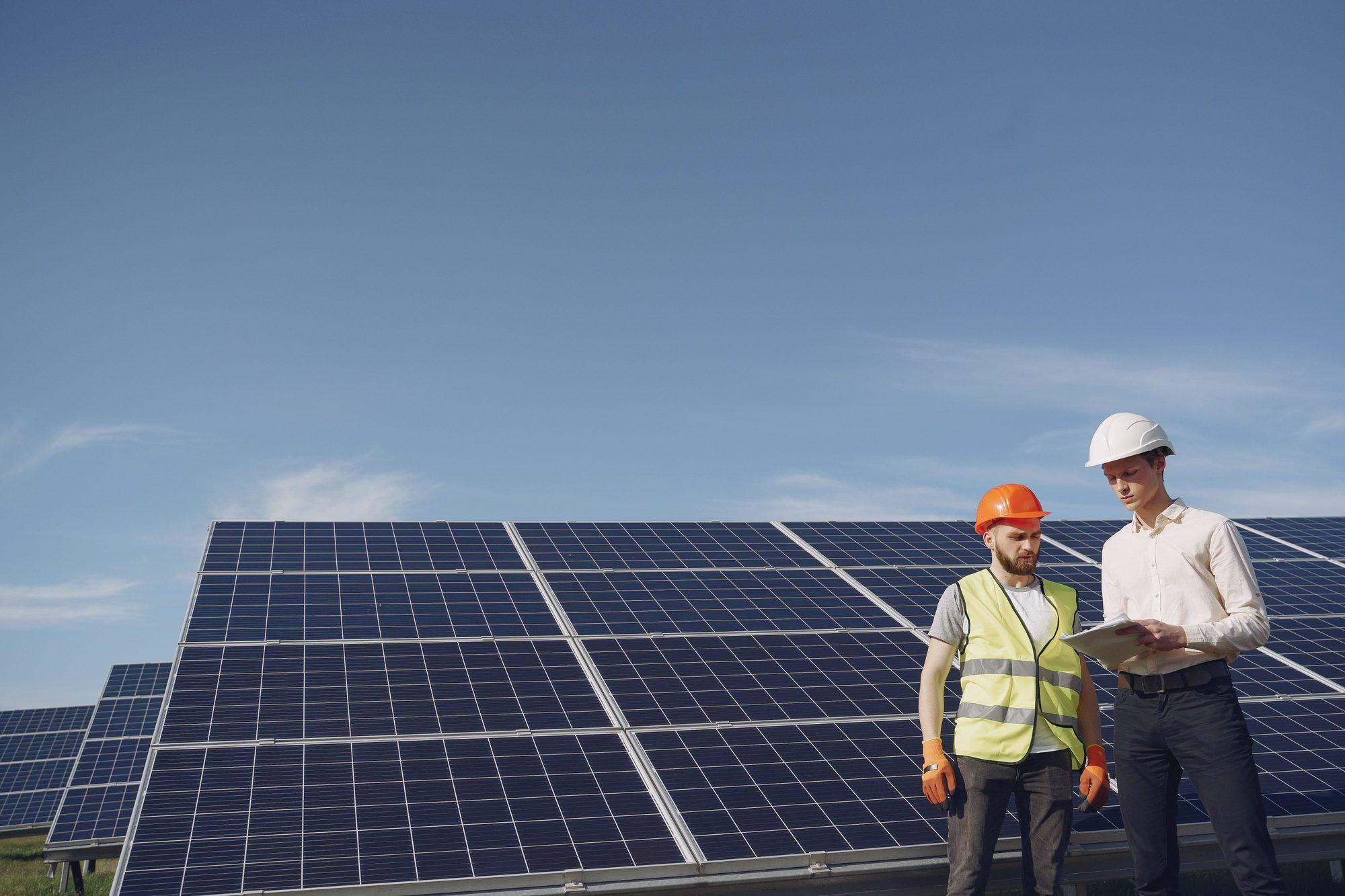Due tecnici con casco protettivo davanti a un impianto fotovoltaico